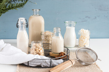 Types of alternative milks in bottles on a rustic tablecloth. Crystal jars full of seeds ,cereal...