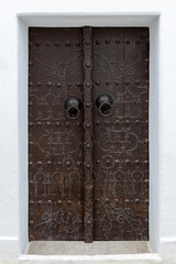 Old wooden door with metal rivets in medina of Hammamet, Tunisia. Traditional ornament and architecture details in North Africa