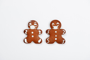 The hand-made eatable gingerbread little men with face masks on white background