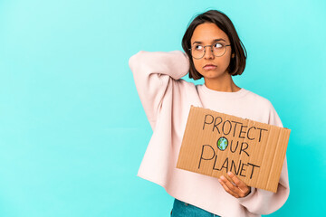 Fototapeta na wymiar Young hispanic mixed race woman holding a protect our planet cardboard touching back of head, thinking and making a choice.