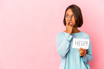 Young hispanic mixed race woman holding a help poster relaxed thinking about something looking at a copy space.