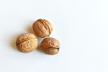Walnuts (Juglans regia) in shell on white wooden background, close-up, top view.