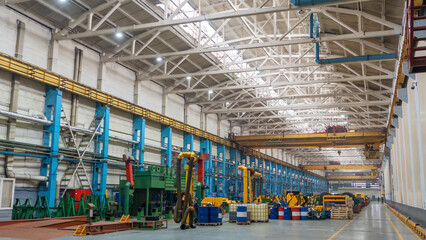 Yellow overhead crane with linear traverse and hooks in engineering plant shop. Industry concept.