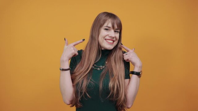 Pointing fingers at cheeks. Cheerful posing with finger on cheek. Health, beauty concept smiling young. Face of beautiful aiming. Cute funny showing puffed. Young attractive woman, dressed green shirt