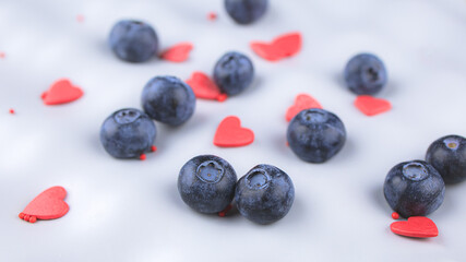 blue blueberries and red hearts scattered on a gray background, close-up, top view