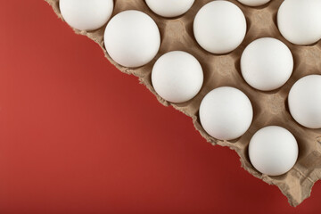 Container of white eggs on red background