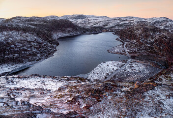 Amazing Arctic landscape with a high-altitude frozen lake Icy winter road through the tundra hills in Teriberka. Amazing colorful Arctic landscape