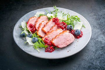 Modern Style Gourmet Entenbrust Filet mit Rucola Salat Preiselbeeren Relish serviert als close-up auf einem Design Teller mit Textfreiraum