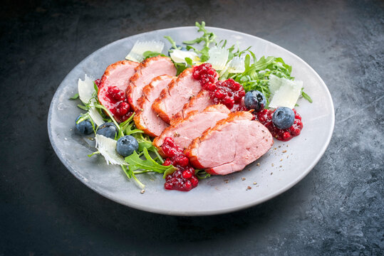 Modern Style Gourmet Entenbrust Filet mit Rucola Salat Preiselbeeren Relish serviert als close-up auf einem Design Teller mit Textfreiraum