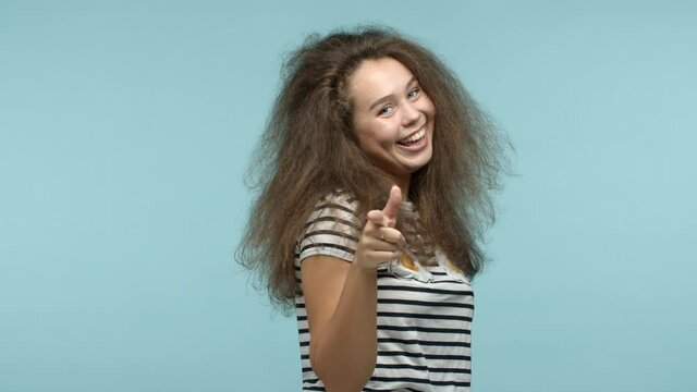 Slow motion of glamour girl dancing and pointing fingers at camera, need you, congratulating or praising good choice, standing over blue background