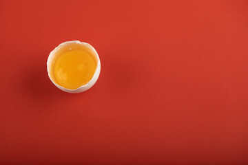 Broken organic egg on red background