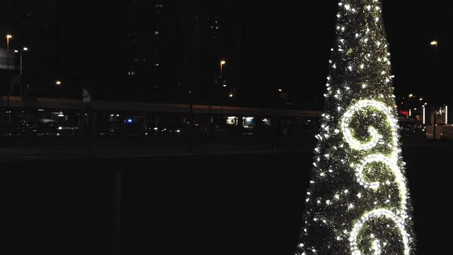 &aacute;rbol de navidad alumbrado con luces  blancas  con fondo negro y coches en movimiento en las inmediaciones de un centro comercial situado en Bizkaia en horario nocturno