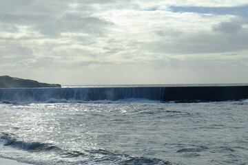 A wave breaking against the jetty at batz-sur-mer harbour. (west of France, december 2020)