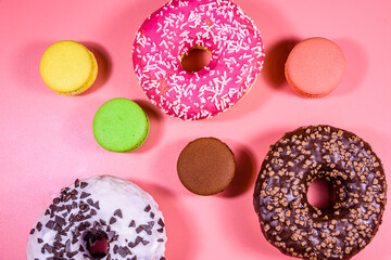 Fresh glazed donuts and french macaroons isolated on a pink background