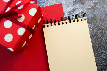 notepad and red gift box on a red-gray background