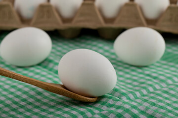White raw egg on wooden spoon