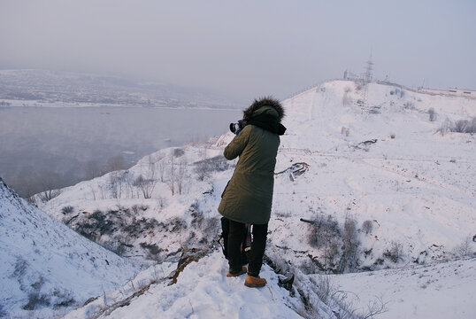 The girl takes pictures from the mountains in winter in a frosty fog