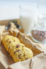 Chocolate chip cookies served with milk on rustic background