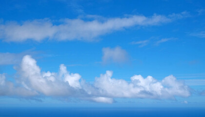 View from the coast of the Easter Island, of blue sky covered by white clouds, over the Pacific Ocean.