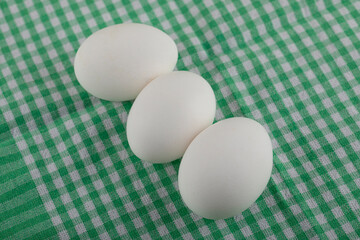 Three uncooked eggs on striped tablecloth