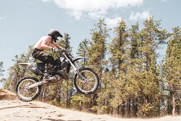 Fototapeta na wymiar dirt bike motocross rider shirtless jump on the air Alberta sand dunes