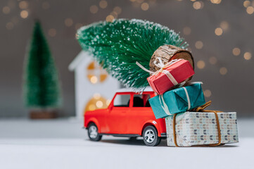 Red car with a Christmas tree on the roof. Against the background of the house. Concept on the theme of Christmas and New Year.