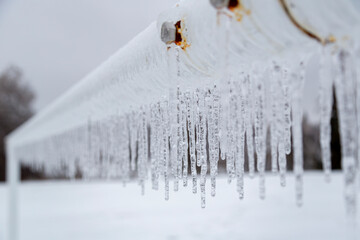 After a severe ice storm, a soccer goalpost is encased in a dense layer of ice, with a string of...