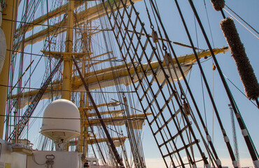 mast of a sailing ship against the sky. The sails have been removed. Rays, stairs, running rigging on the barge. day. Summer. Sunny.