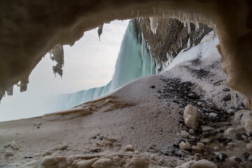 Looking through the ice cave behind Ontario's Niagara Falls as vapor rises over melting icicles