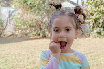 Cute little girl walks on nature and laughs and grimaces looking into the camera. happy childhood and positive emotions. 