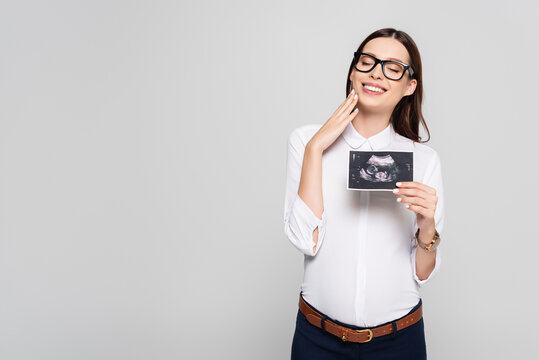  young pregnant businesswoman in glasses holding ultrasound scan isolated on grey