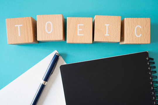 TOEIC writing; 積み木ブロックで作ったTOEICのコンセプト, 黒のノートブック, 白の紙, 青のペン