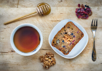 A slice of vegan cake with super fruit and nuts, honey and a cup of tea, hight angle view.