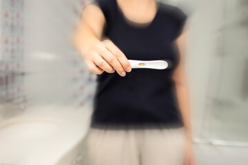 Closeup of woman hold positive pregnancy test. Pregnancy test with two stripes. Baby is coming. New life and maternity leave concept.