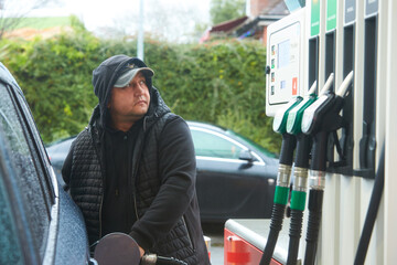A man refueling a car at a petrol station