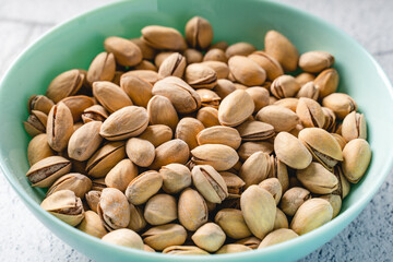 Close up on fresh salted roasted pistachios snack nuts in bowl with selective focus background