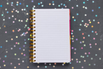 Open blank notepad page on festive dark black background with colorful stars. To Do list, writing...
