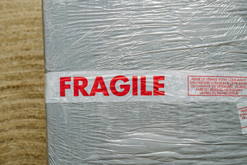 Fragile red scotch inscription on fragile good with special instruction in French language take care of he goods and inspect before signing the delivery