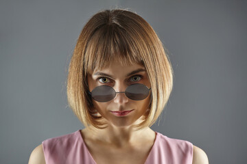 Portrait of a young girl with dark glasses. photo shoot in the Studio on a gray background