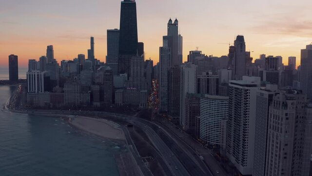 Flying backwards above Chicago downtown and busy road by the beach with city lights
