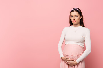  young pretty pregnant woman touching belly isolated on pink