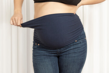 Pregnant woman with maternity pants with hight waist. Jeans for big tummy. Side view