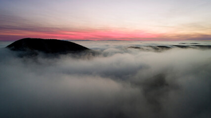 mountain peeking up above the fog at dusk