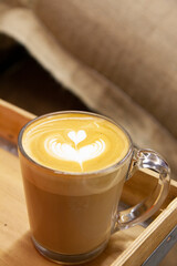cup of coffee, caffee latte on wooden tray with a large burlap sack of coffee bean