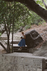 A girl in a blue skirt is walking in a beautiful forest