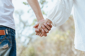 Couple of lovers holding hands walking on wood bridge in the forest.  Newlywed couple on a romantic vacation