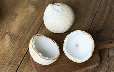 cut half coconut and fresh coconuts for food on wooden table.