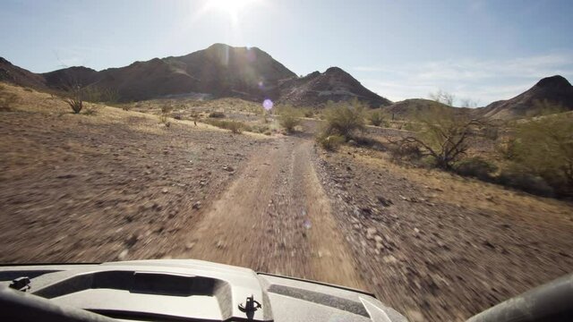Driving on the slope of a mountain with a quad 4x4 atv towards the sun at dirt roads in the hills of Quartzsite, AZ, USA.