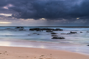 Moody morning bay seascape with rain clouds and rocks