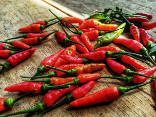 red bird's eye chilies on a wooden plank background